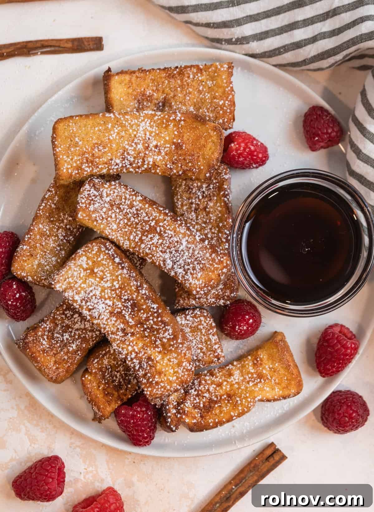 Crispy Air Fryer French Toast Sticks 3 Overhead view of a beautiful plate of crispy cinnamon sugar-coated Air Fryer French Toast sticks, artfully arranged with a small glass bowl of rich maple syrup, perfect for dipping.