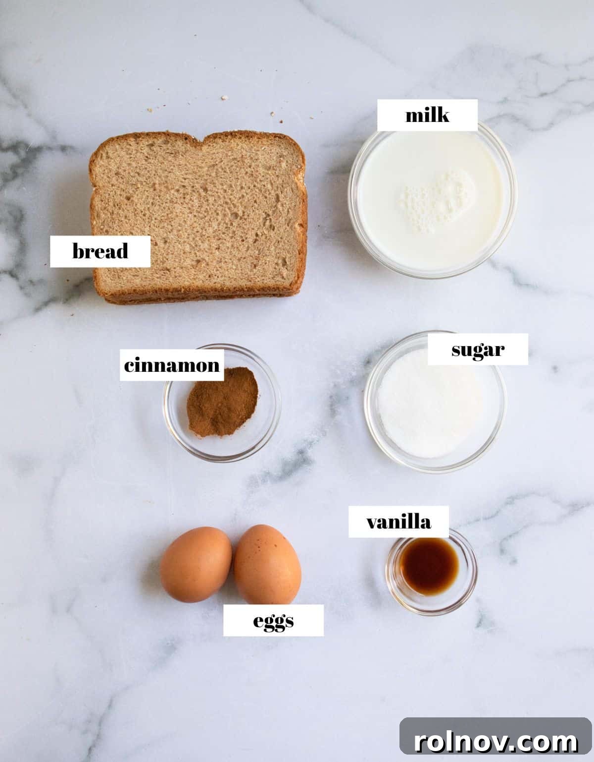 Crispy Air Fryer French Toast Sticks 4 A beautifully arranged flat lay photo showcasing the essential ingredients for Air Fryer French Toast Sticks: slices of bread, fresh eggs, a bottle of vanilla extract, a bowl of granulated sugar, and ground cinnamon, all labeled for clarity.