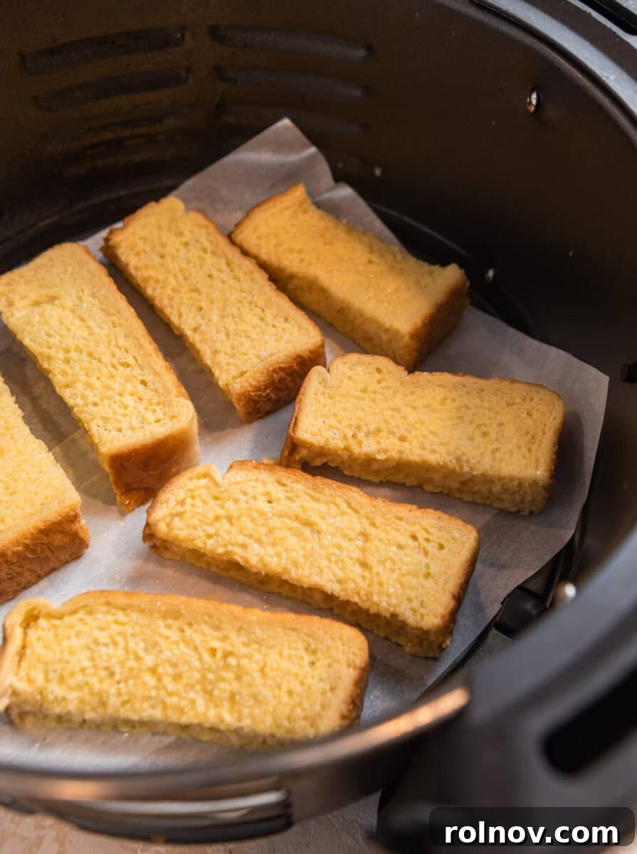 Crispy Air Fryer French Toast Sticks 6 French toast sticks neatly lined in an air fryer basket, arranged in a single layer and ready for cooking to achieve perfect crispiness.