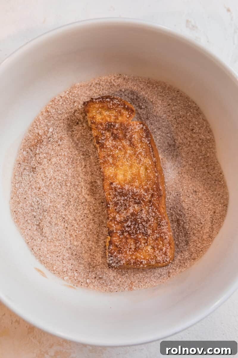 Crispy Air Fryer French Toast Sticks 8 A single air-fried French toast stick beautifully coated with cinnamon sugar, resting in a pristine white dish, ready to be enjoyed.