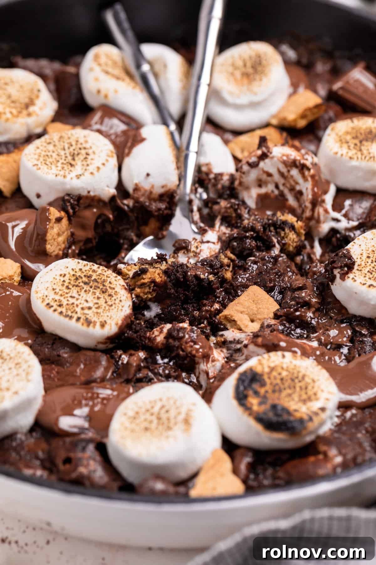 Gooey S'mores Skillet Brownie 2 S'mores brownie skillet topped with torched marshmallows, ready to be scooped.