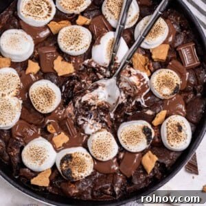 Gooey S'mores Skillet Brownie 9 S'mores brownie skillet topped with marshmallows, more chocolate and graham crackers with serving spoons in the center.