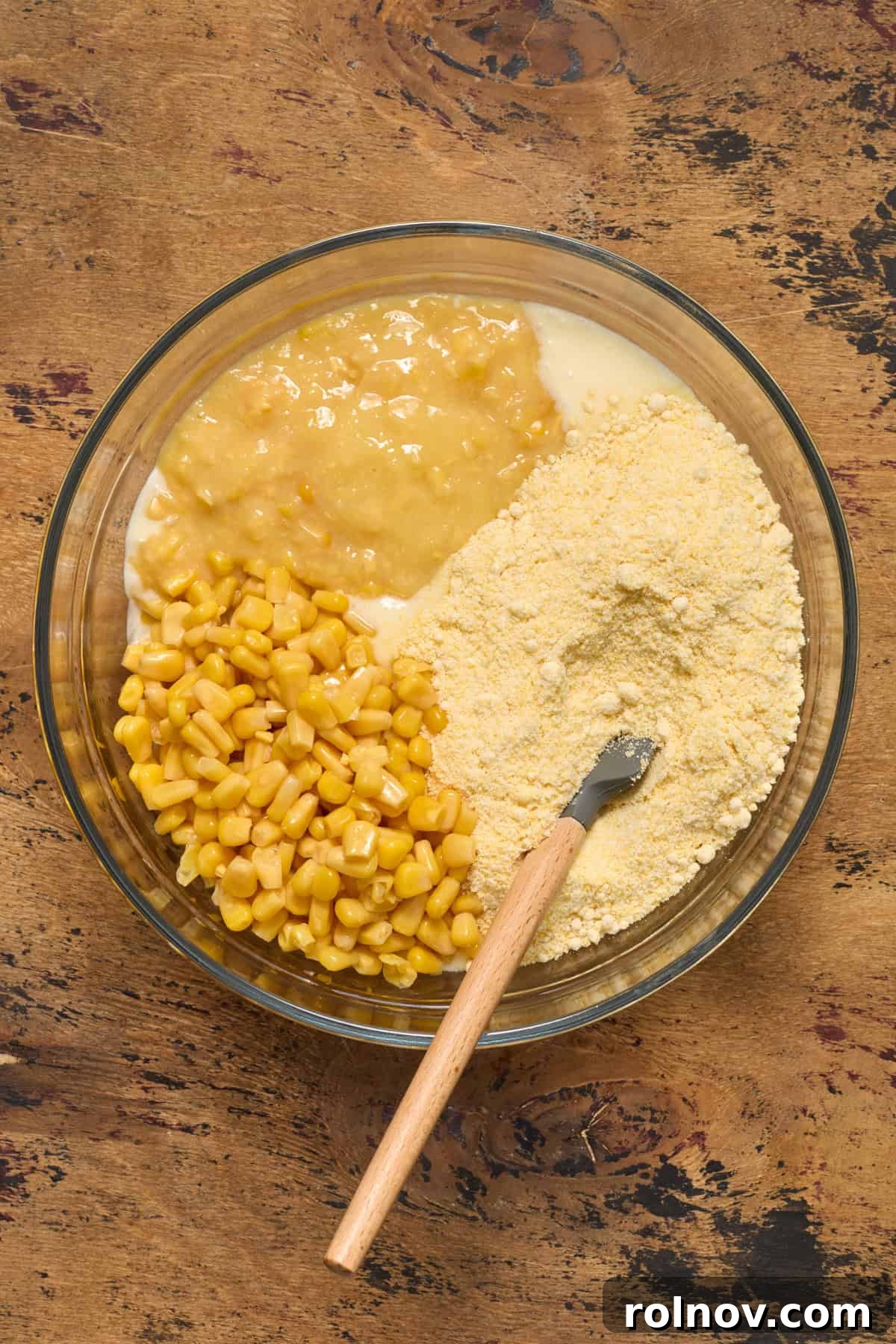 Golden Honey Cornbread Bake 7 Cornbread mix, corn and creamed corn in bowl with spatula.