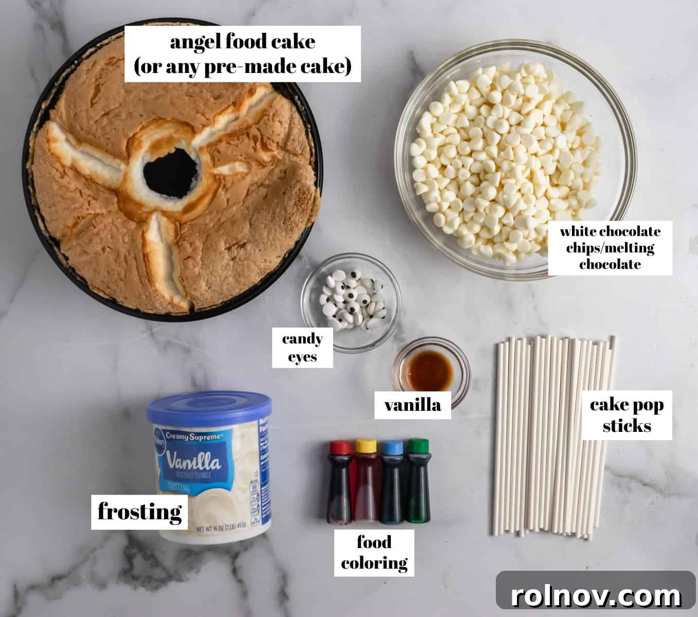 All the necessary ingredients laid out on a clean counter: Angel Food cake, vanilla frosting, white chocolate chips, vanilla extract, and food coloring, ready for baking fun.