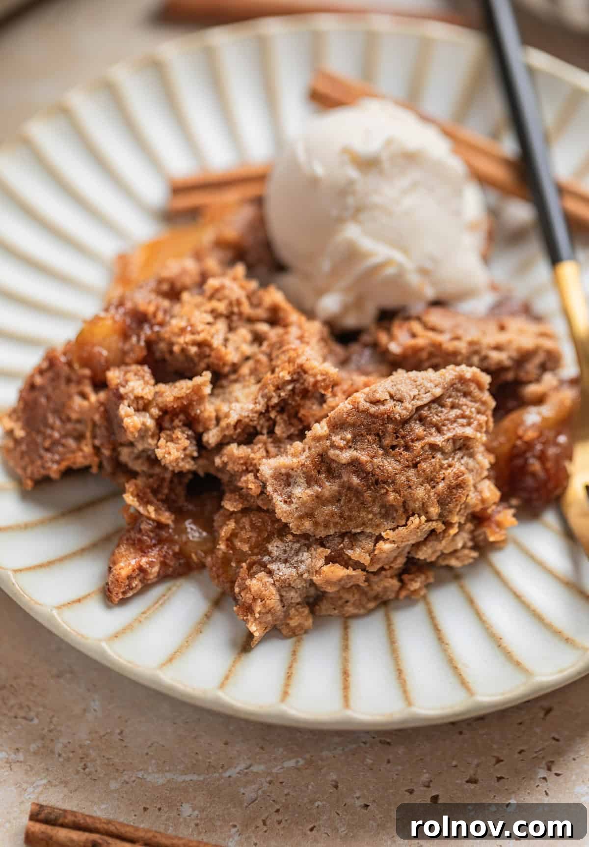 Effortless Golden Apple Bake 2 Apple dump cake served on a dish with a fork and a scoop of vanilla ice cream, ready to be enjoyed.