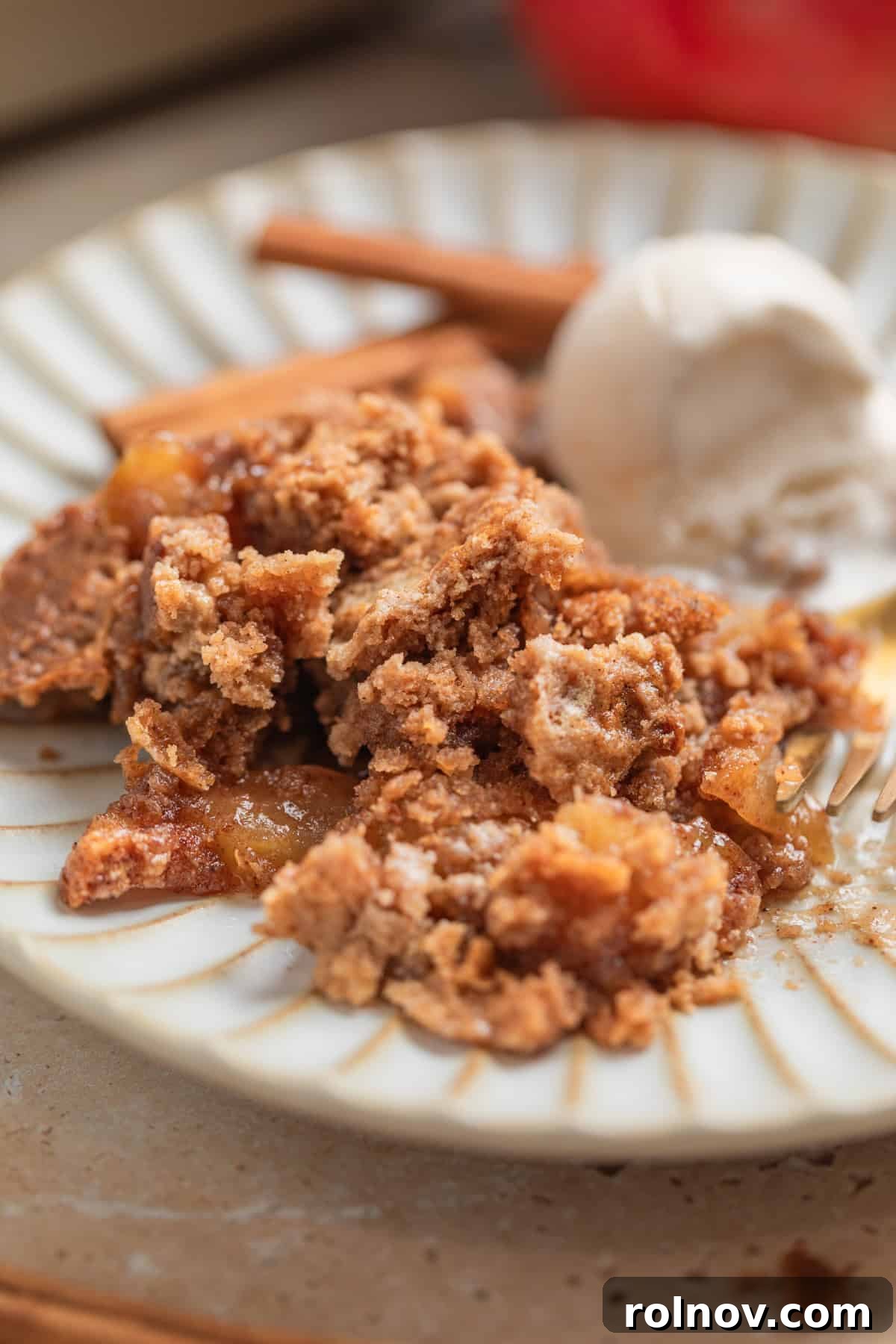 Effortless Golden Apple Bake 11 A beautifully plated serving of the apple dump cake, topped with a generous scoop of vanilla ice cream and accompanied by a fork, ready to be enjoyed as a perfect autumn dessert.