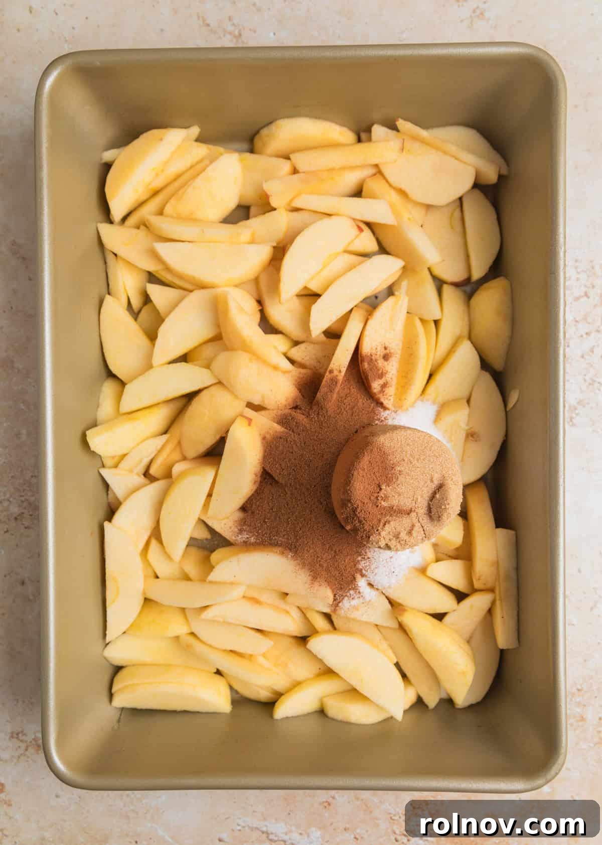Effortless Golden Apple Bake 5 Cinnamon, brown sugar, and white granulated sugar sprinkled generously over the sliced apples in the pan, ready for tossing.