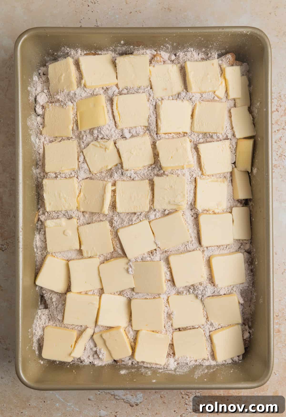 Effortless Golden Apple Bake 8 Thin slices of cold butter meticulously arranged to cover the entire surface of the dry spice cake mix layer, ready for baking.