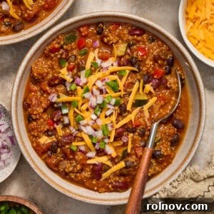 A comforting bowl of chili featuring quinoa, pumpkin, and beans, with a spoon ready to scoop.