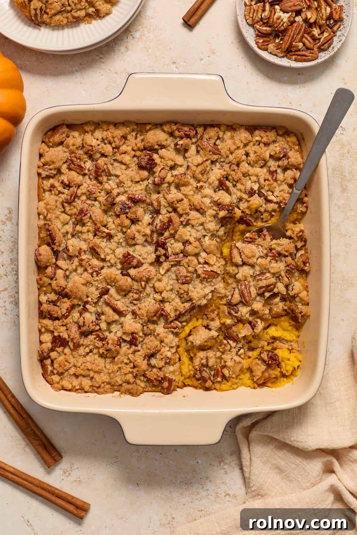 Butternut squash casserole in a baking pan, with a serving spoon scooping out a generous portion.