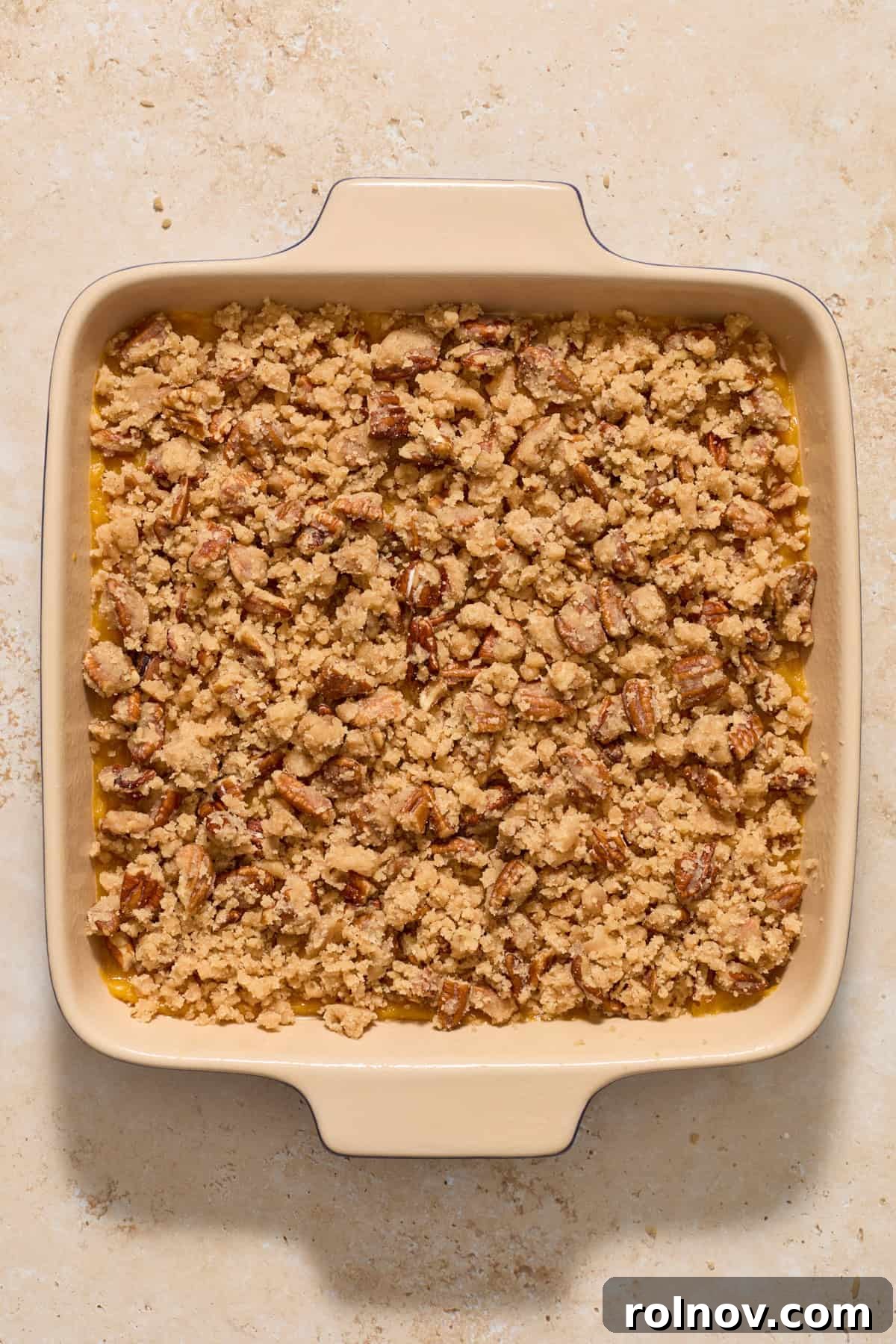 The butternut squash casserole in its baking pan, beautifully topped with the pecan crumble, ready for the oven.