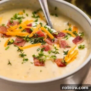 Creamy Instant Pot Potato Leek Soup 9 Beige bowl with potato soup topped with bacon, cheese, chives and sour cream.
