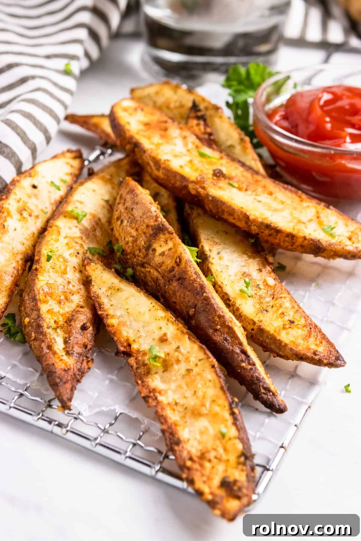 Crispy Air Fryer Parmesan Potato Wedges on wax paper with a side of ketchup.