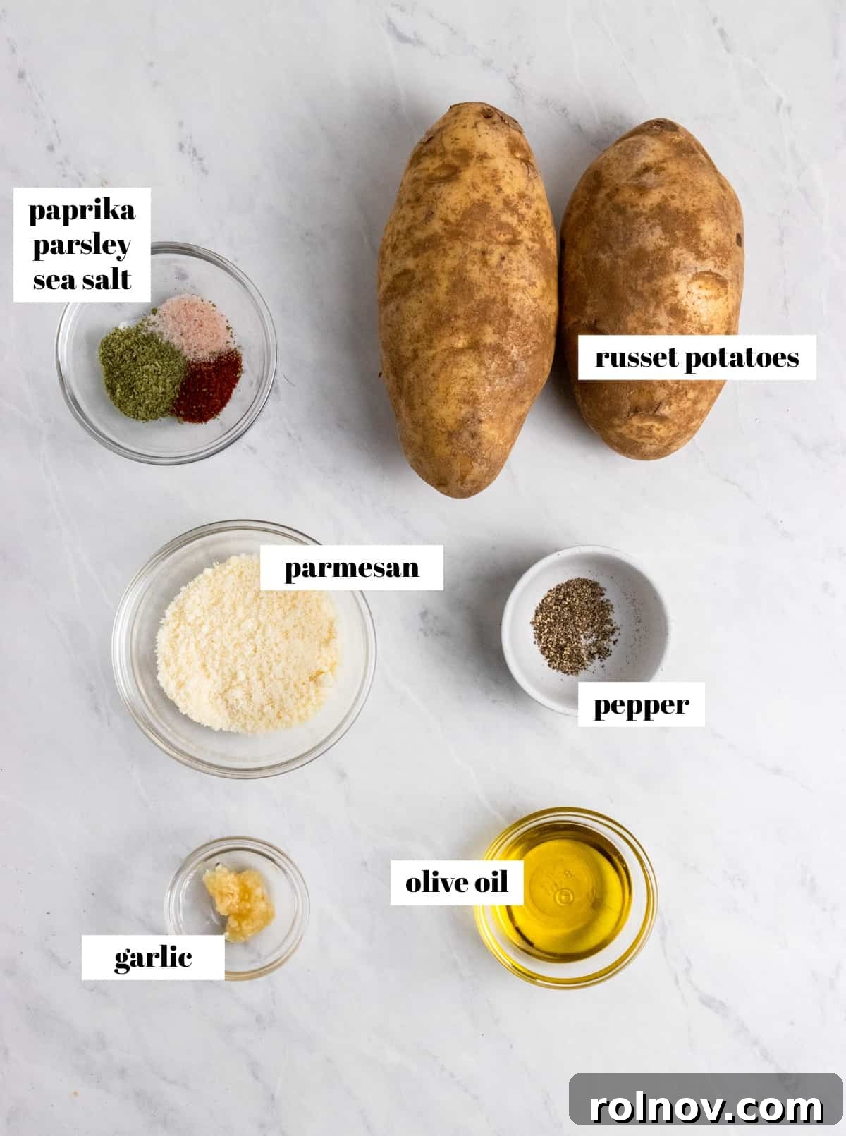 Ingredients for air fryer potato wedges including potatoes, olive oil, parmesan, and spices, laid out on a kitchen counter.