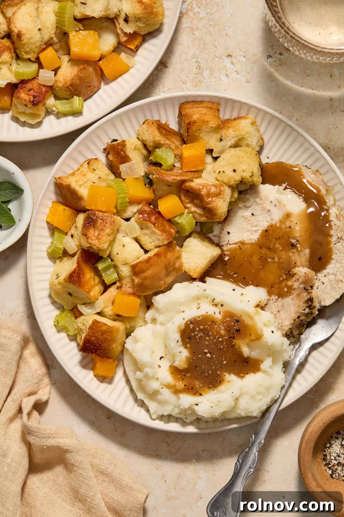 Butternut squash stuffing on a plate alongside roasted turkey and creamy mashed potatoes, ready for a holiday feast.