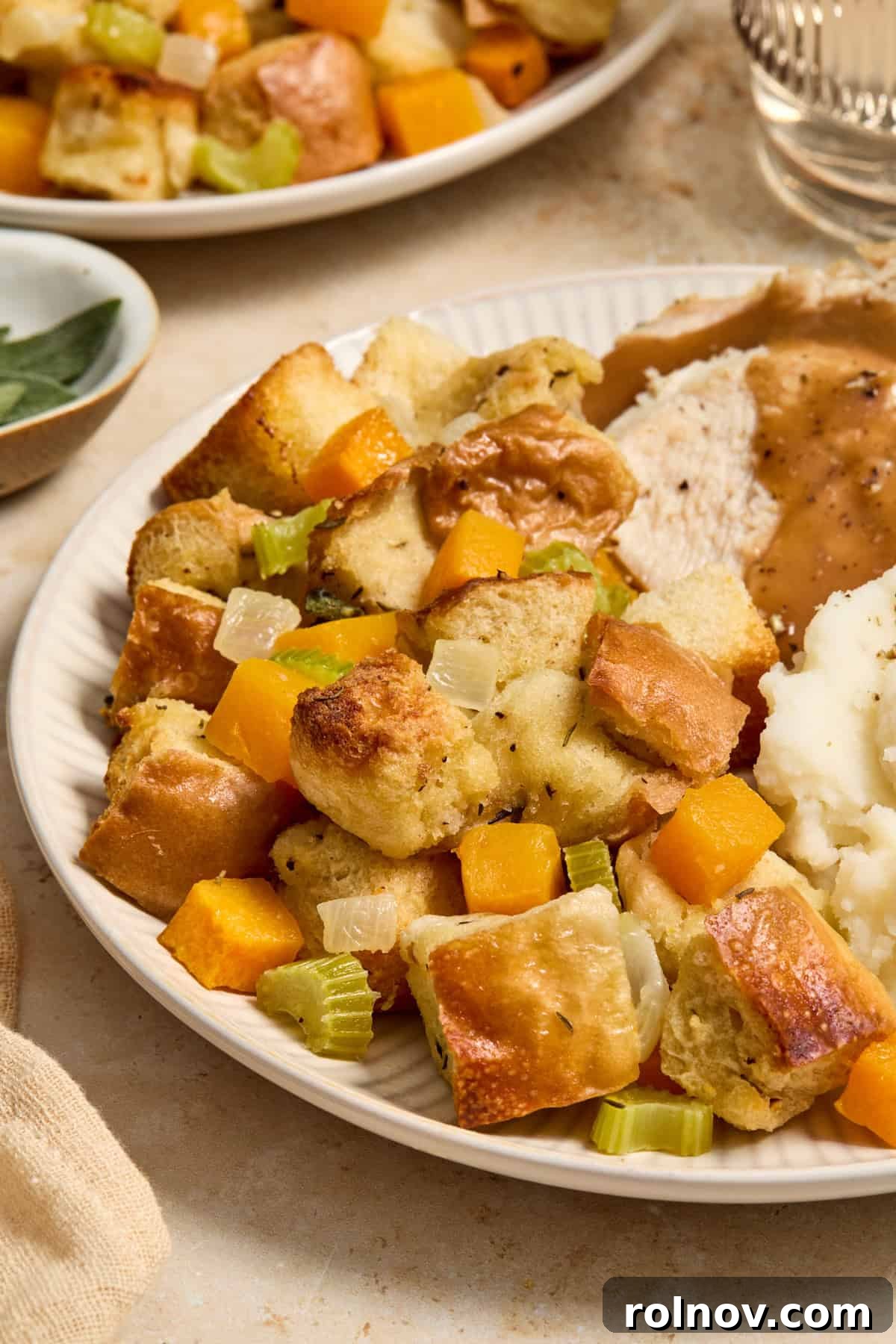 A festive plate showcasing a generous serving of butternut squash stuffing, roasted turkey, creamy mashed potatoes, and rich gravy, symbolizing a complete holiday meal.