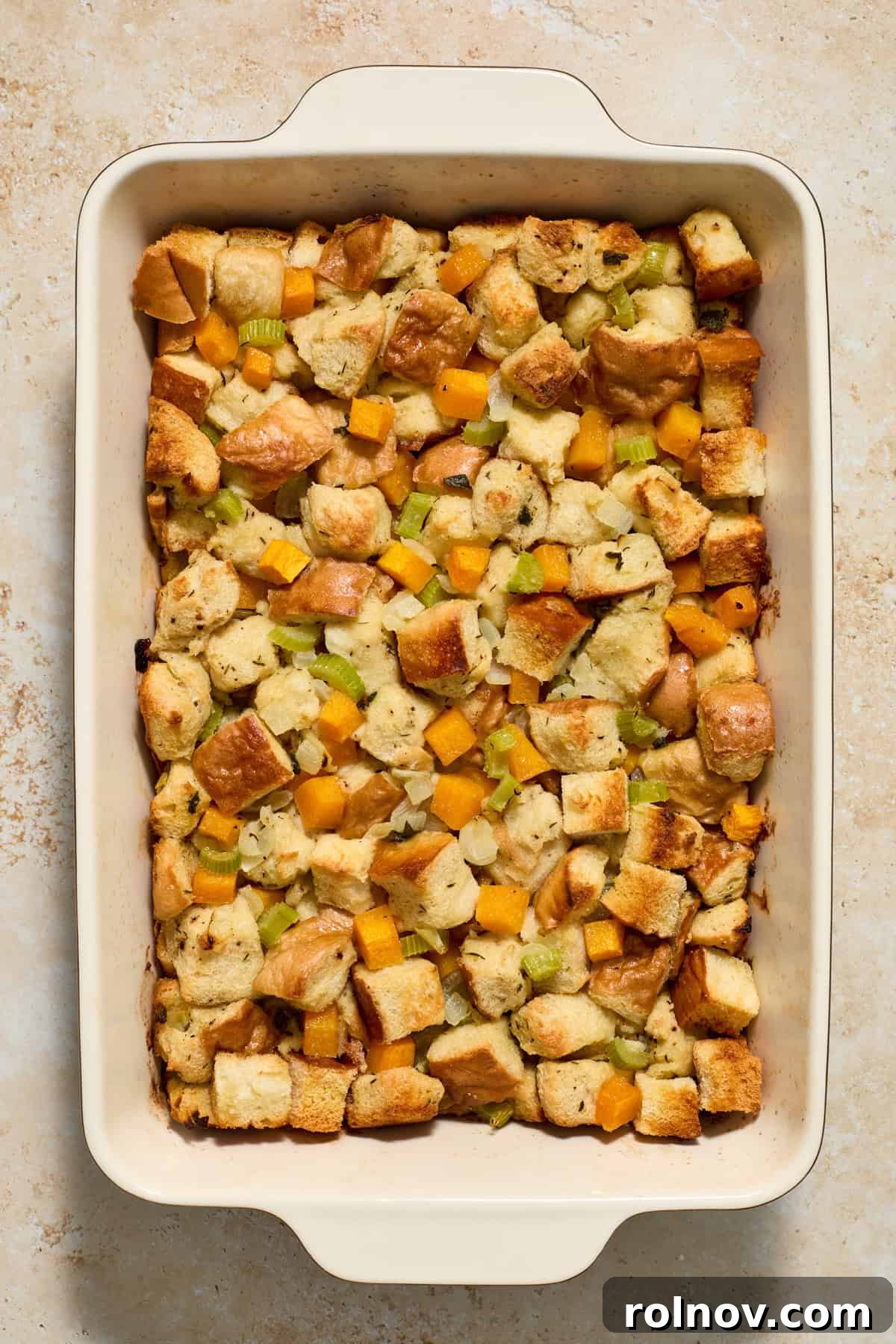 A baking pan of golden brown, freshly baked butternut squash stuffing, just removed from the oven and steaming.