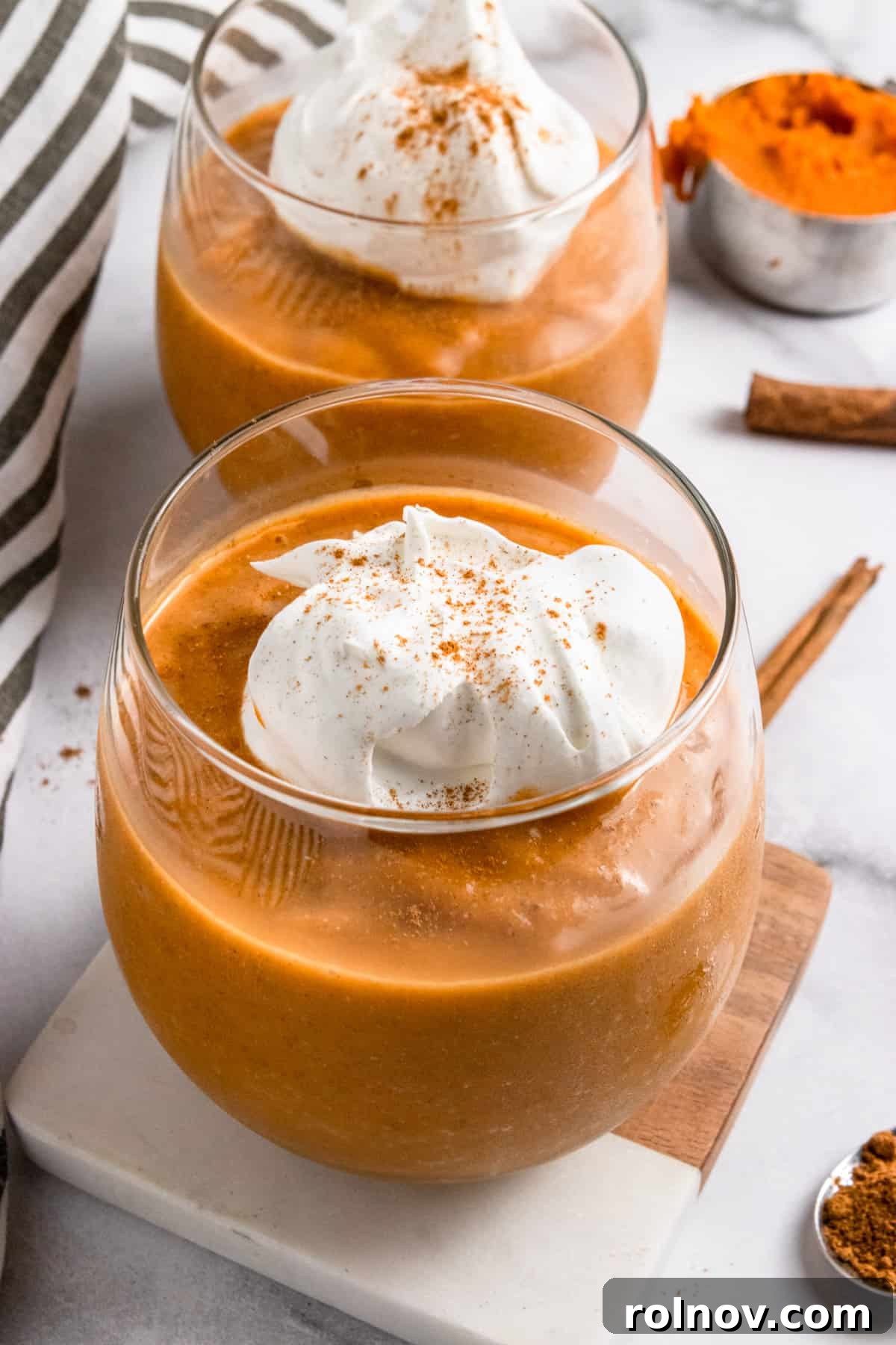 Spiced Pumpkin Pie Smoothie 2 Pumpkin smoothie in glass with whipped cream on top, ready to be enjoyed.