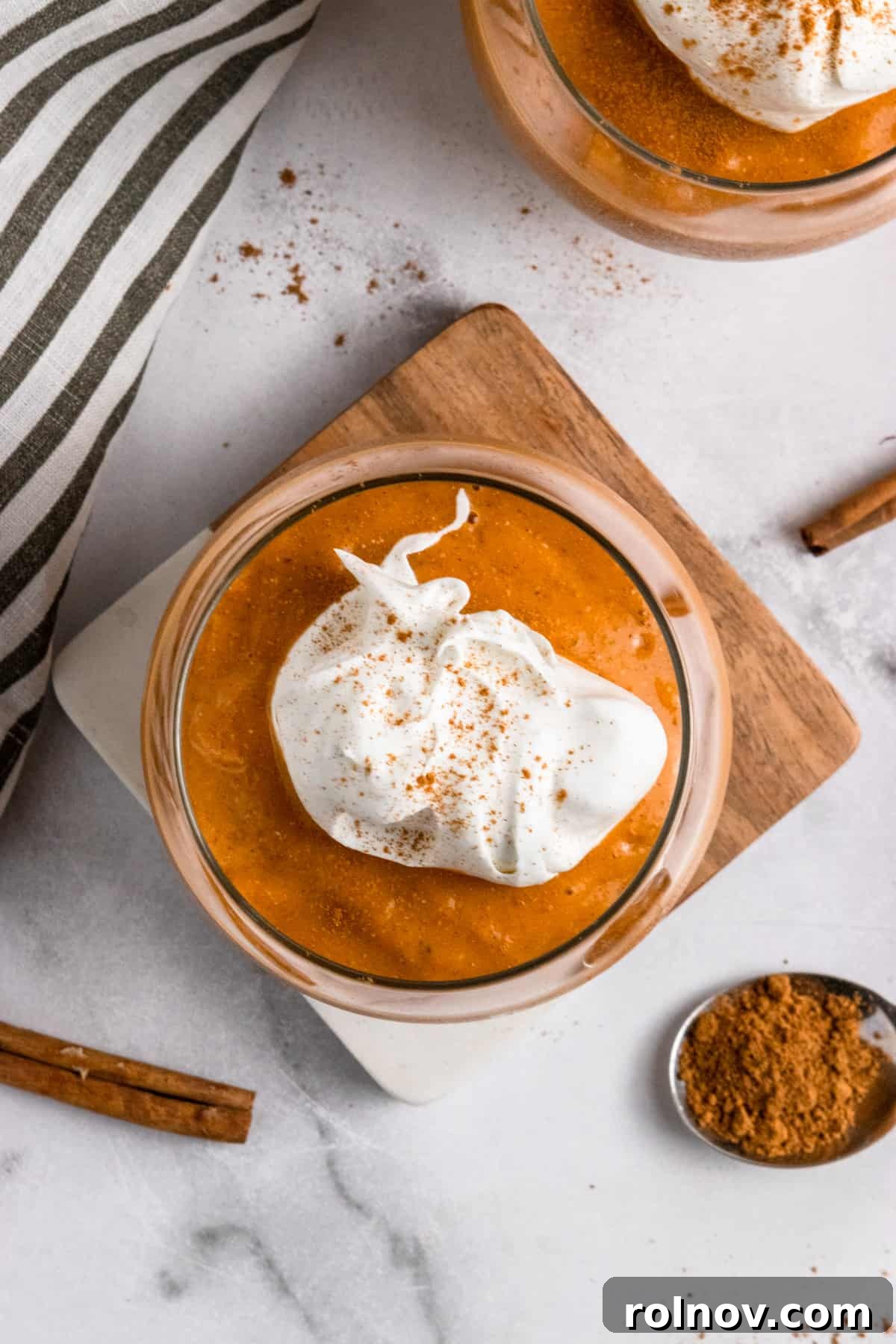 Spiced Pumpkin Pie Smoothie 3 Overhead view of a pumpkin smoothie in a glass with a generous swirl of whipped cream on top.