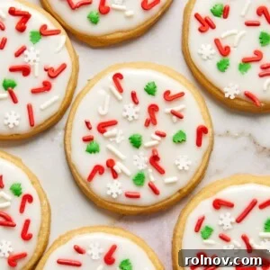 Buttery Holiday Shortbread Delights 14 Iced shortbread cookies with Christmas sprinkles arranged on counter.