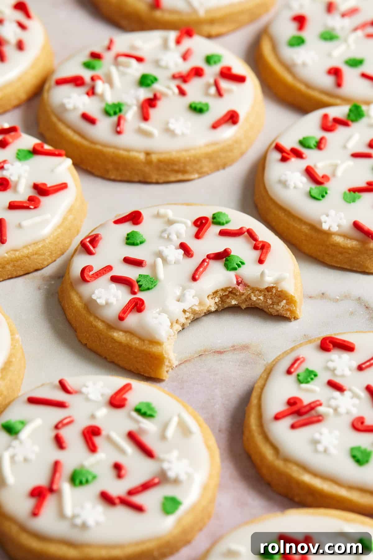 Buttery Holiday Shortbread Delights 3 Christmas iced cookies arranged on surface with bite taken out of center cookie.