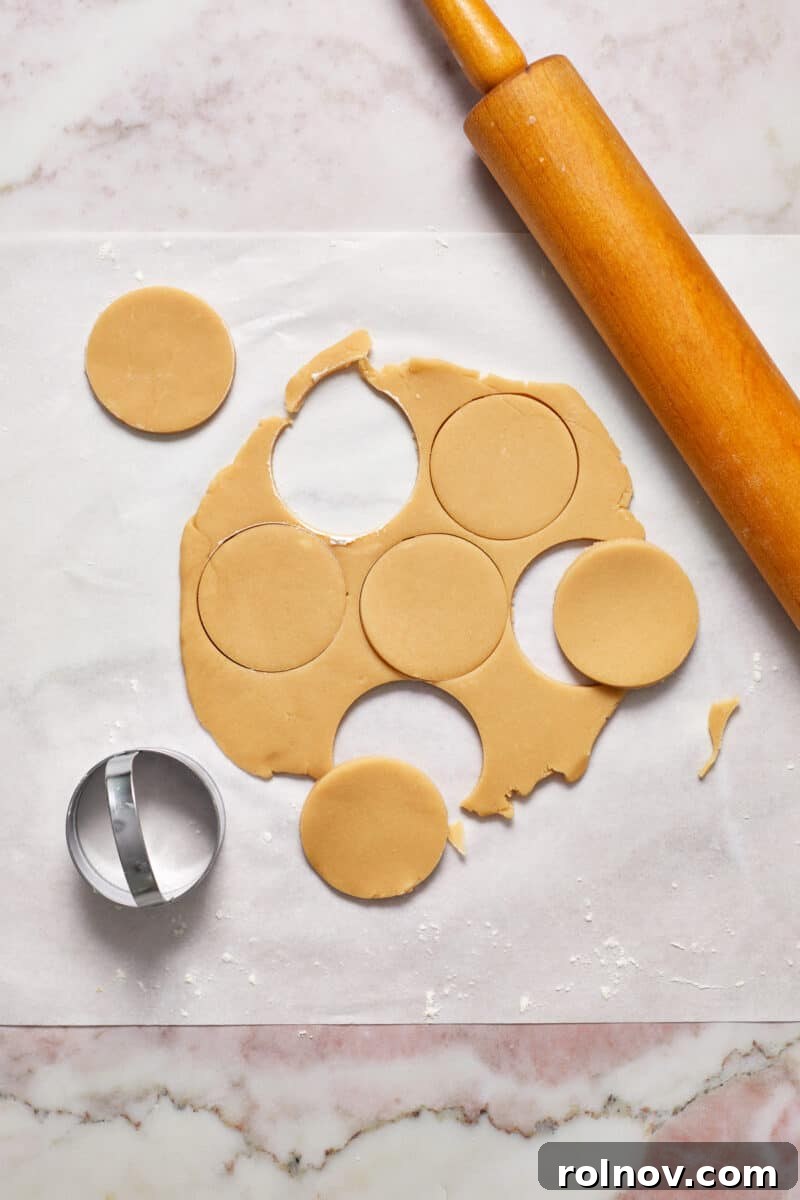 Buttery Holiday Shortbread Delights 9 Rolled shortbread cookie dough on parchment with cookie cutter and rolling pin.
