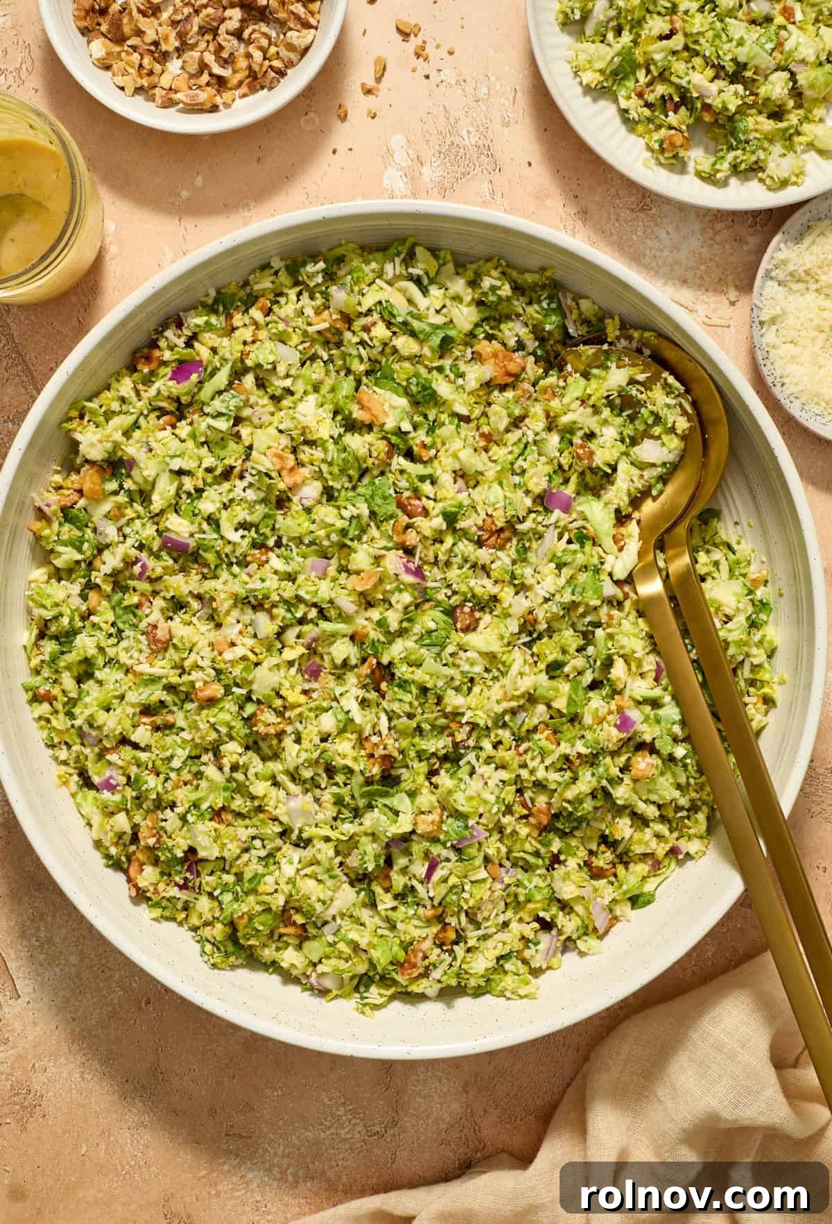 Zesty Brussels Sprout Slaw 2 Shaved brussel sprout salad in serving bowl with serving utensils propped in the salad bowl.