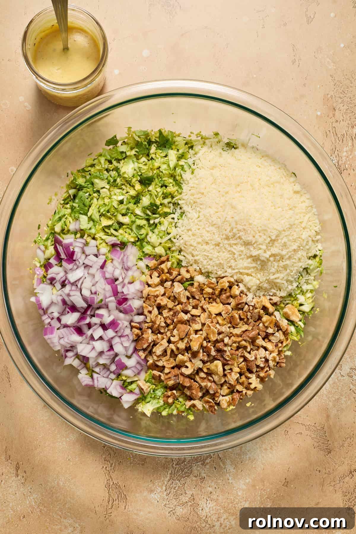 Zesty Brussels Sprout Slaw 6 Shredded brussels sprouts in large bowl with red onion, walnut pieces and shredded parmesan before mixing.