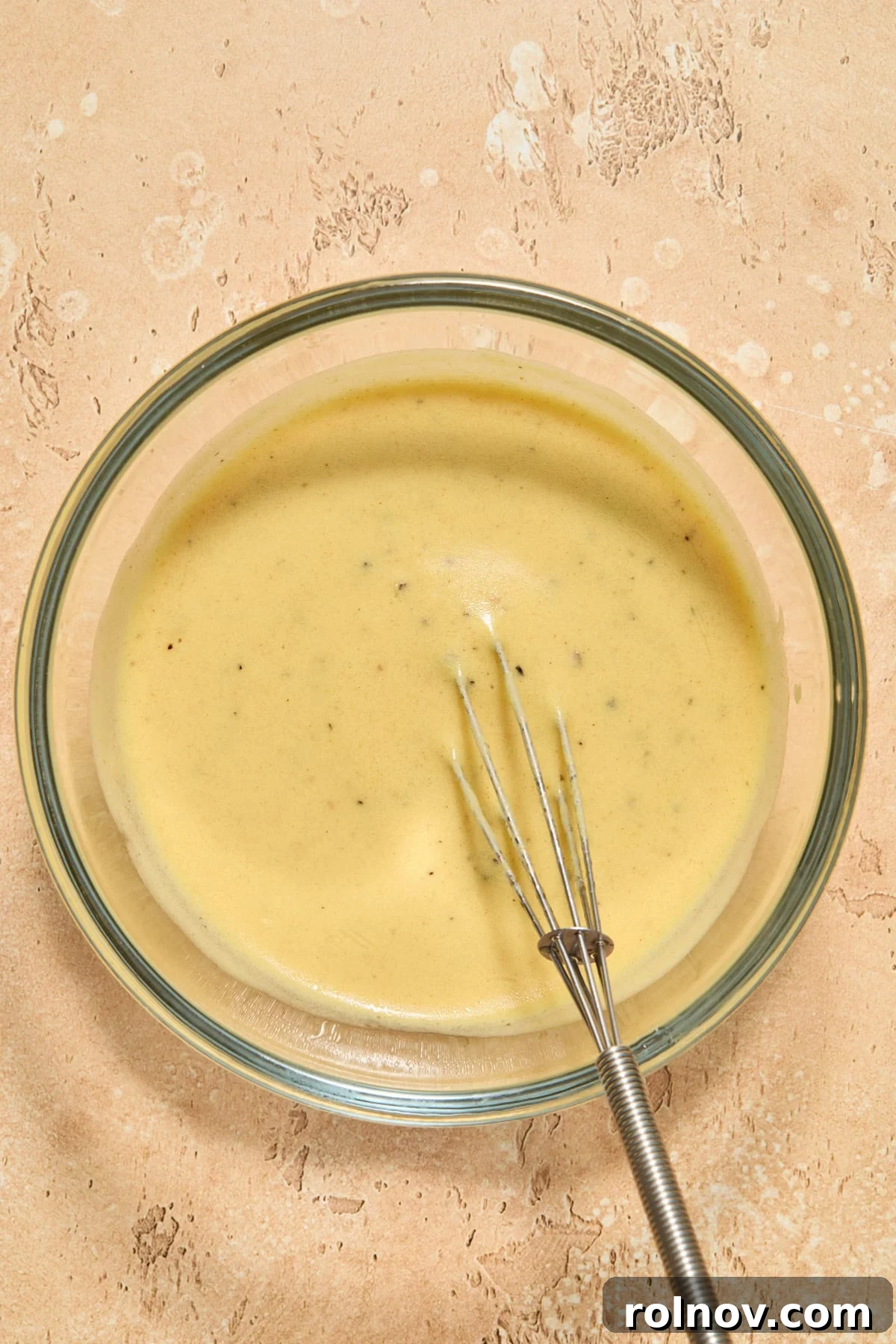 Zesty Brussels Sprout Slaw 8 Whisk in glass bowl with lemon dijon dressing.
