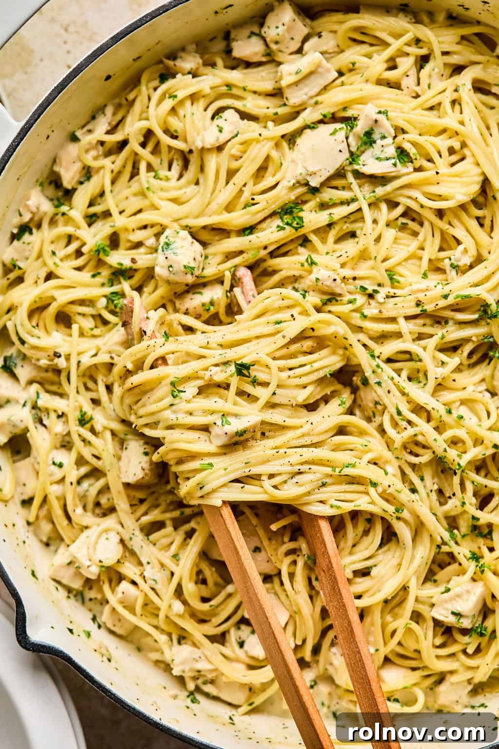 Effortless Creamy Chicken Alfredo 2 One pot easy chicken alfredo in pan with tongs wrapping pasta.