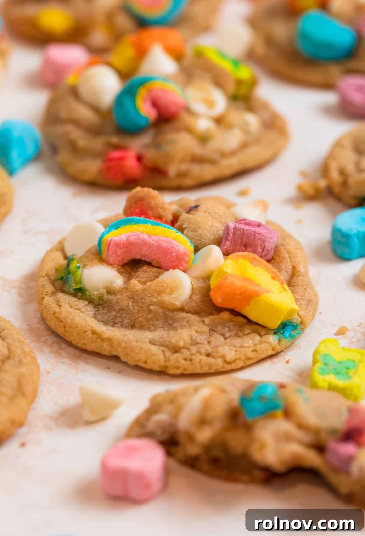 Charmed Bites 11 A stunning arrangement of baked Lucky Charms cookies, complete with colorful marshmallows and white chocolate chips, beautifully displayed on a counter alongside extra ingredients.