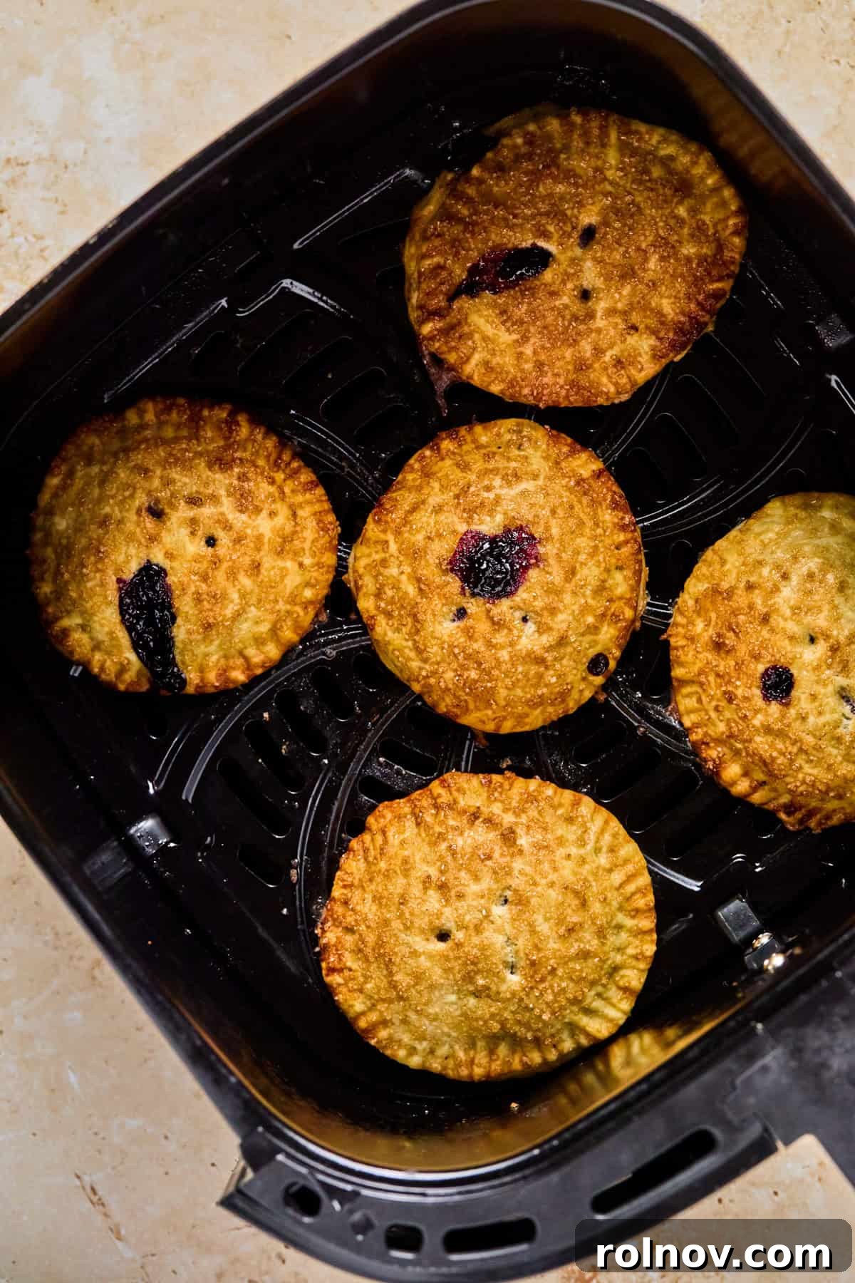 Crispy Air-Fried Blueberry Turnovers 16 Beautifully cooked, golden-brown air fryer mini pies cooling in the air fryer basket.