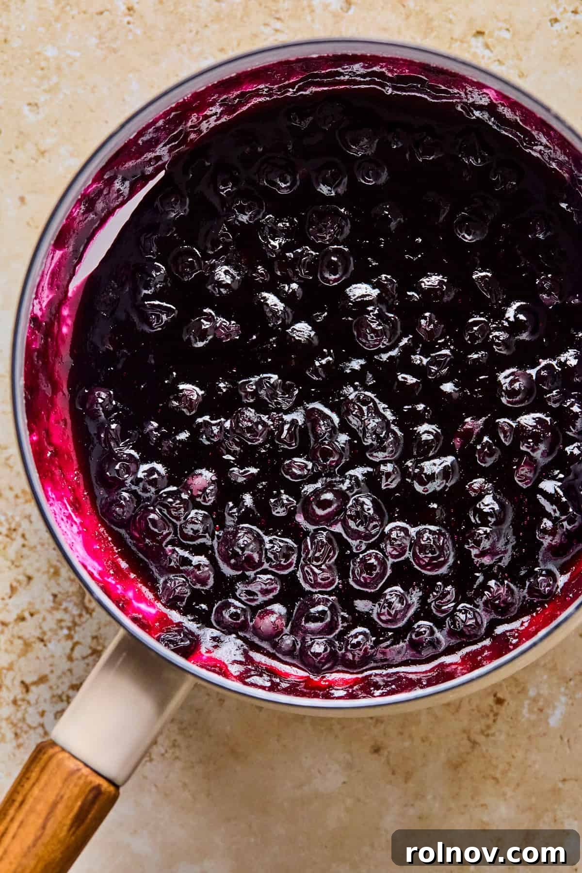 Crispy Air-Fried Blueberry Turnovers 10 Blueberry sauce thickening in a pot on the stove, appearing rich and glossy.