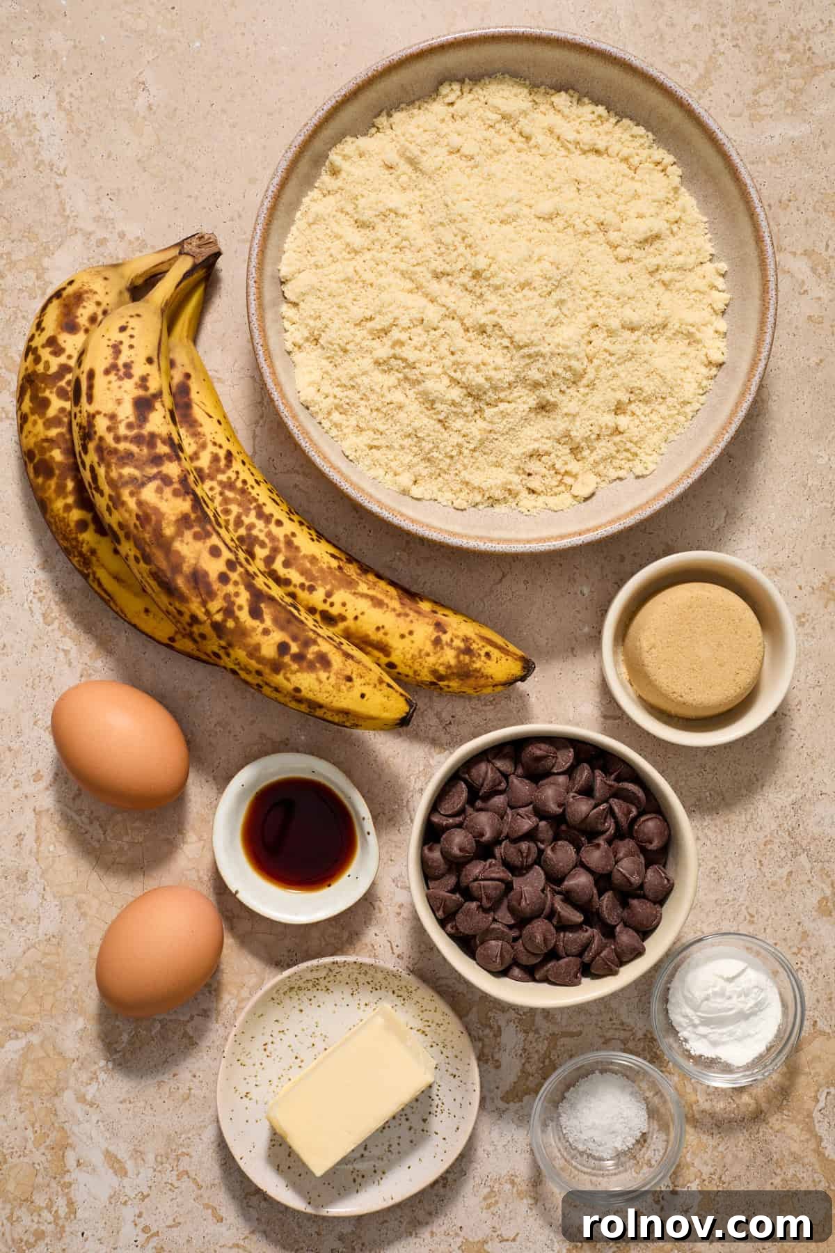 Tender Almond Banana Muffins 3 Butter, baking powder, bananas, brown sugar and other ingredients arranged on counter.