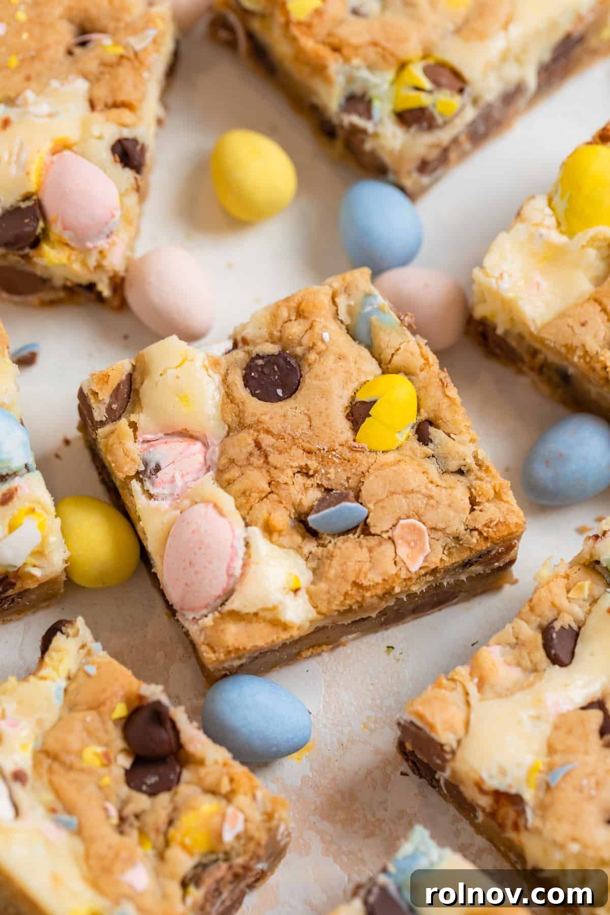 Easter Mini Egg Cheesecake Bars 9 Mini egg cheesecake cookie bars sliced on counter.