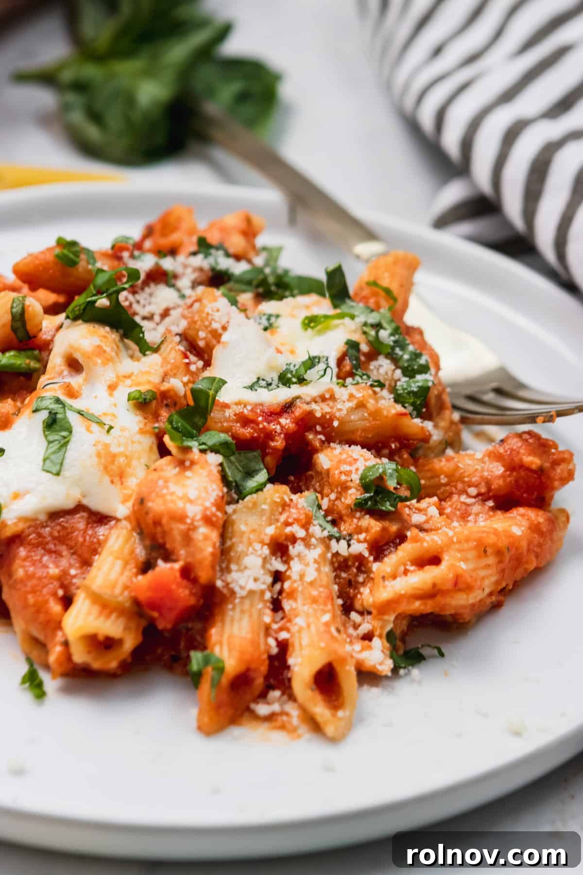 Golden Baked Chicken Parm 2 Chicken parmesan pasta on plate with melted cheese and fork.