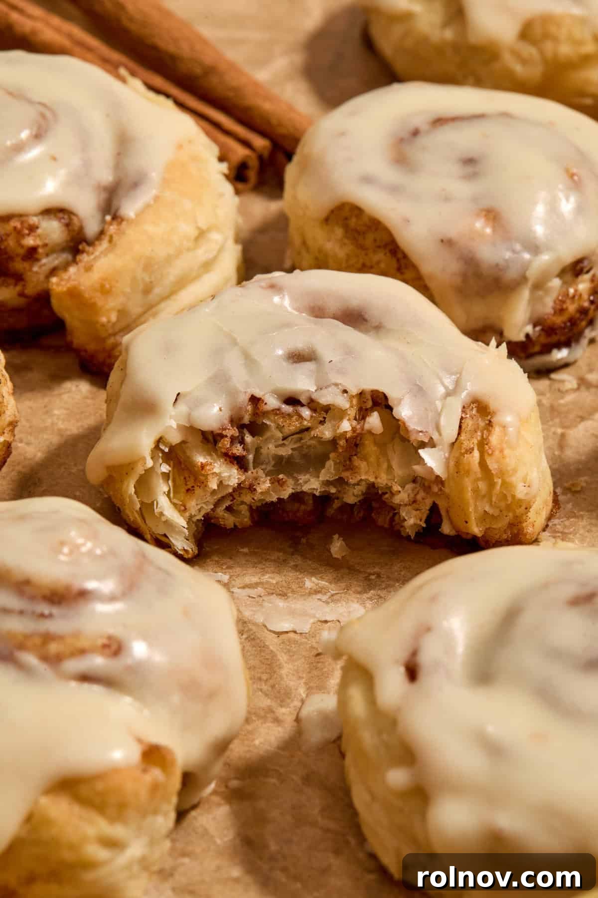 Flaky Cinnamon Swirls 13 Puff pastry cinnamon rolls on parchment with bite taken out of cinnamon roll.