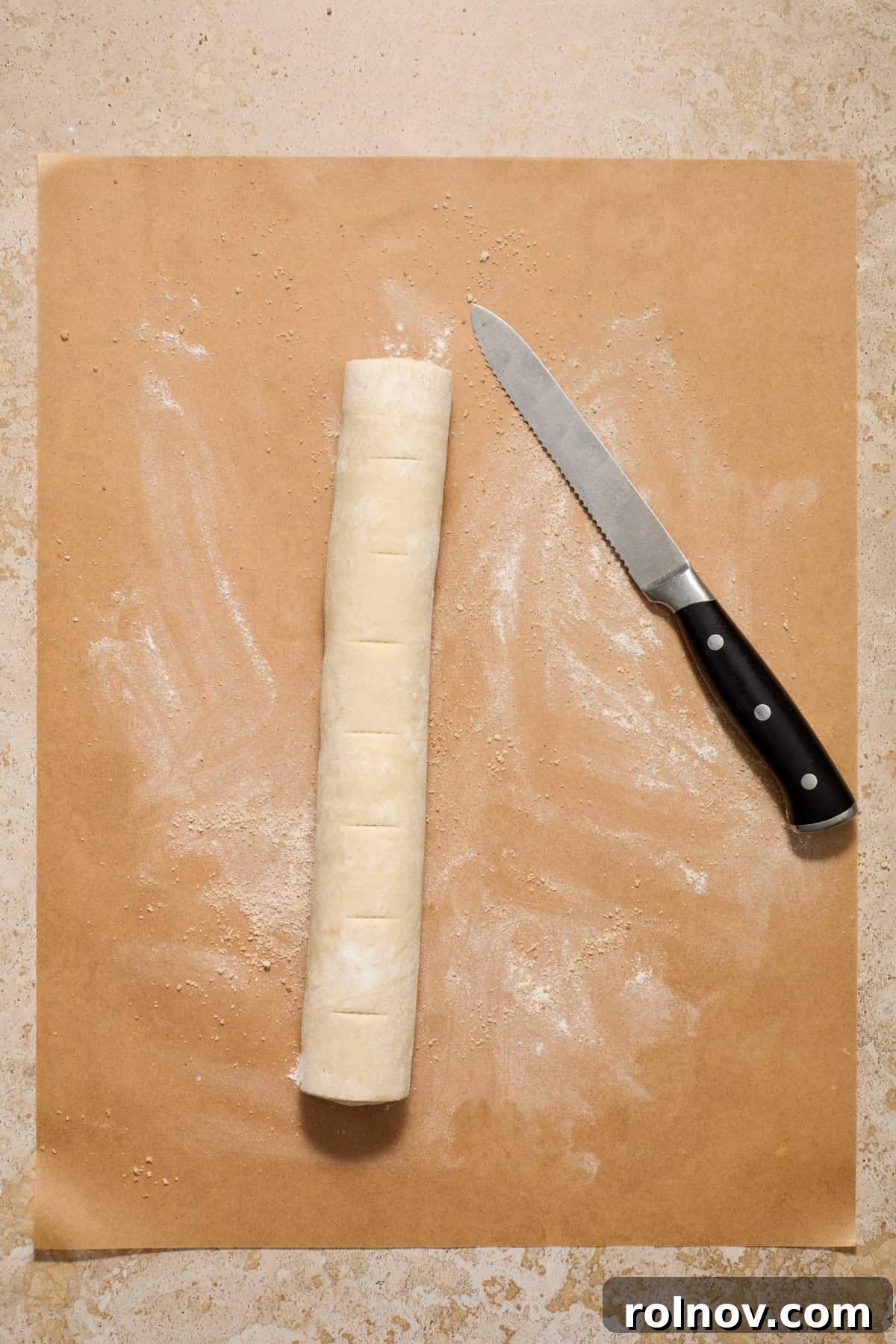 Flaky Cinnamon Swirls 8 Lines cut on cinnamon roll log on parchment.