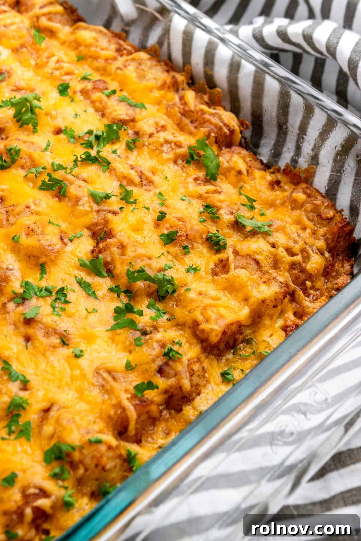 Crispy Tater Tot Breakfast Bake 6 Close-up shot of the finished Ham and Cheese Breakfast Casserole with Tater Tots, featuring golden, crispy tots and melted cheese on top, garnished with fresh herbs.