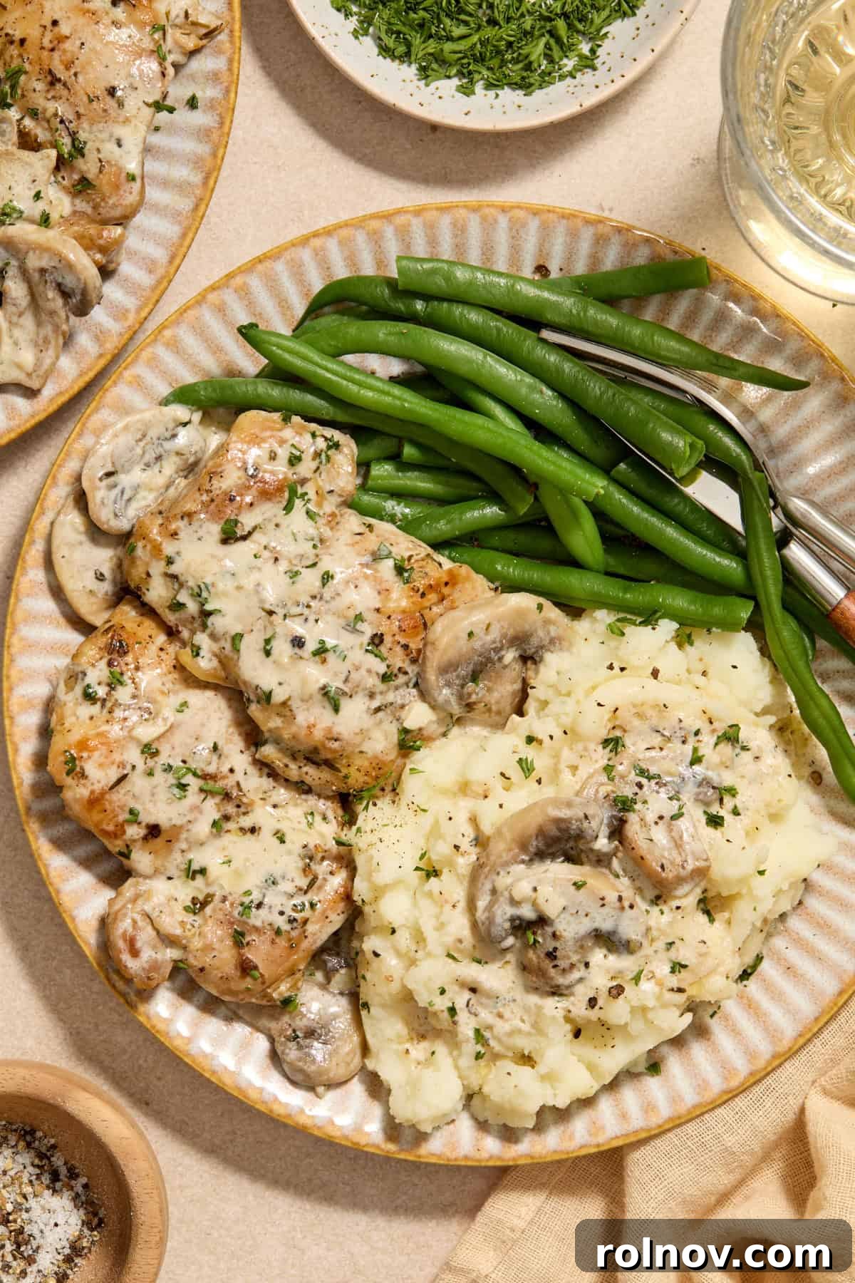 Golden Chicken Thighs in Velvety Mushroom Sauce 2 Cream plate with chicken thighs in creamy mushroom sauce and green beans and mashed potatoes.