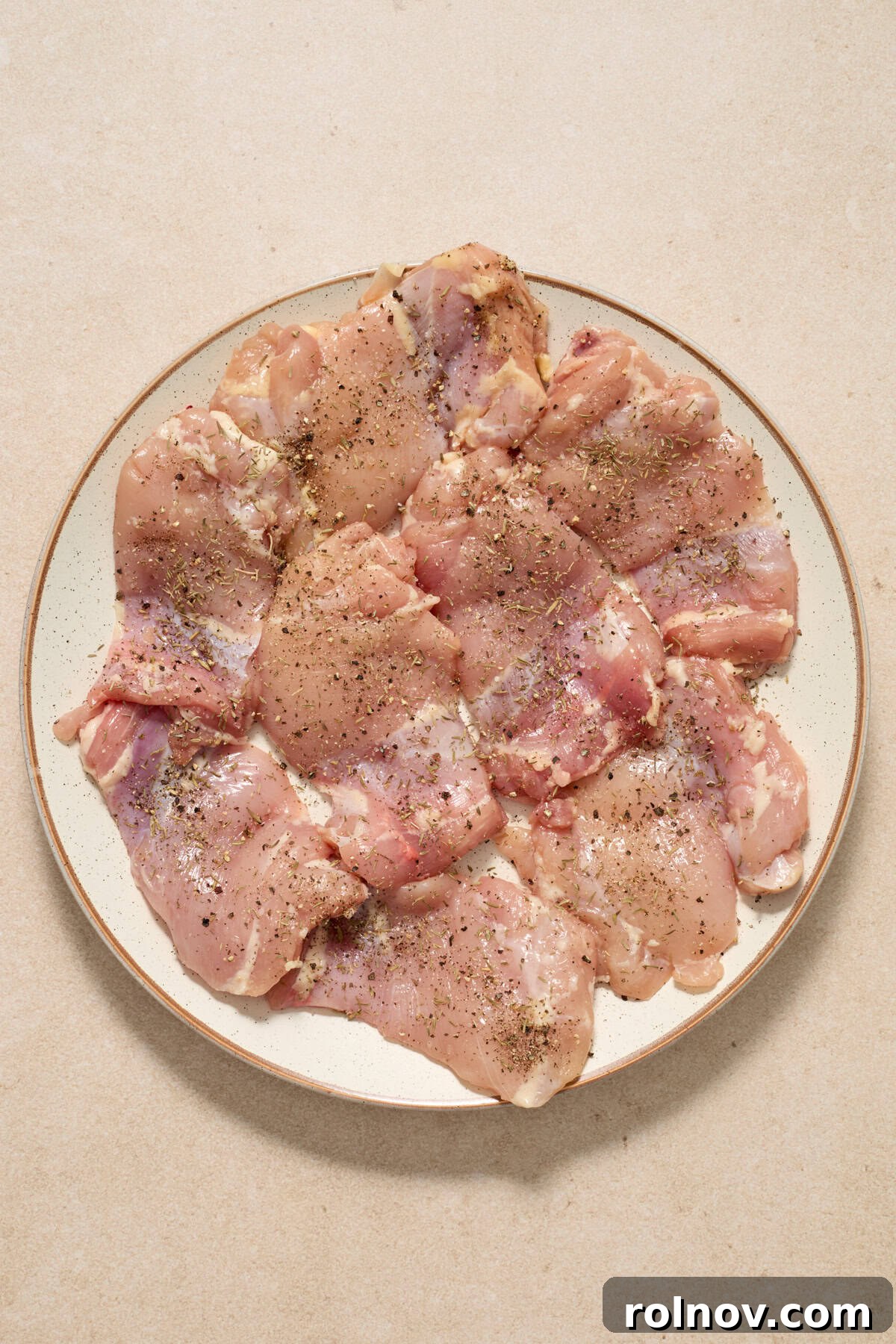 Golden Chicken Thighs in Velvety Mushroom Sauce 4 Chicken thighs with seasoning arranged on plate before cooking.