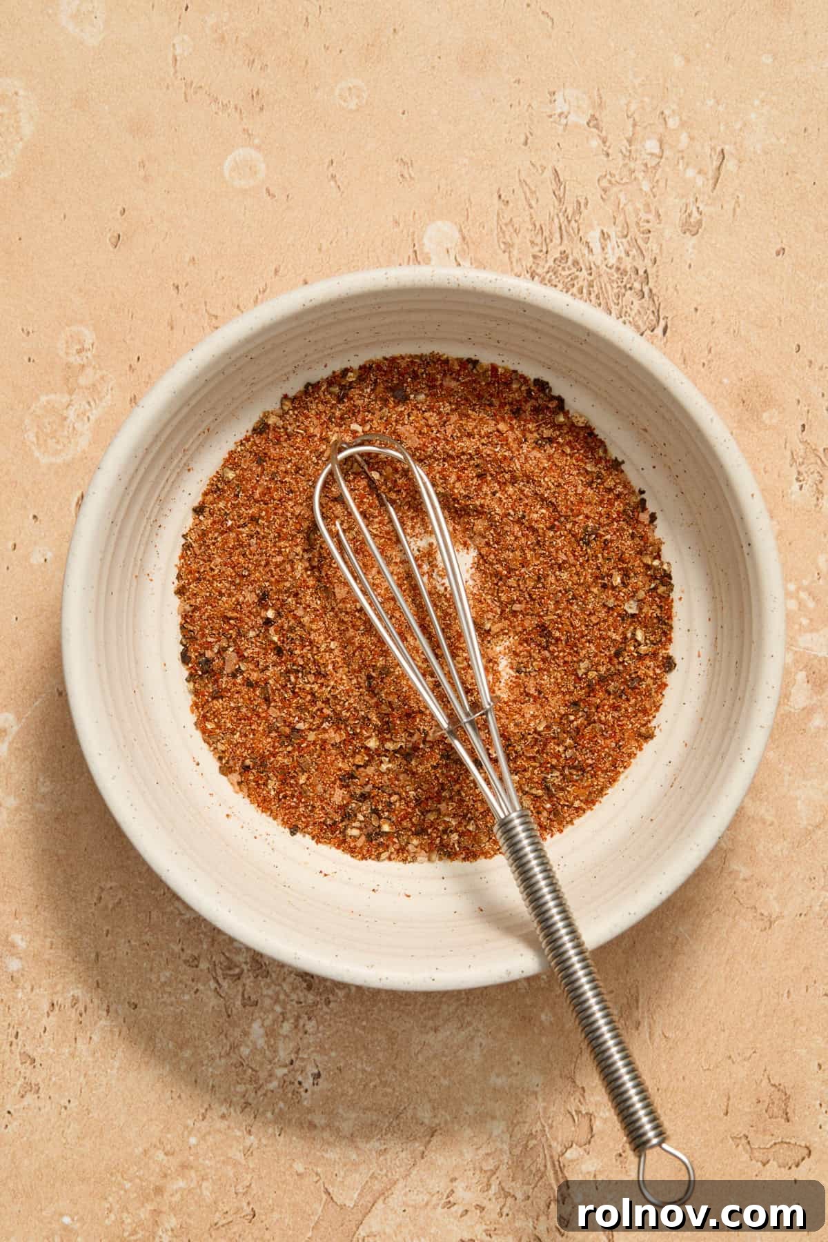 Bowl with whisk and chicken rub.