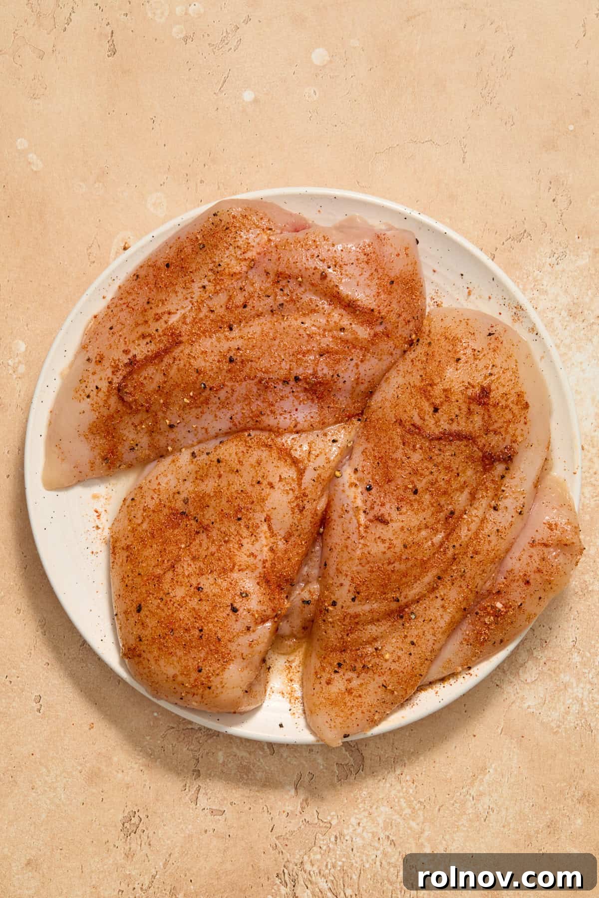 Seasoned chicken breasts on plate.
