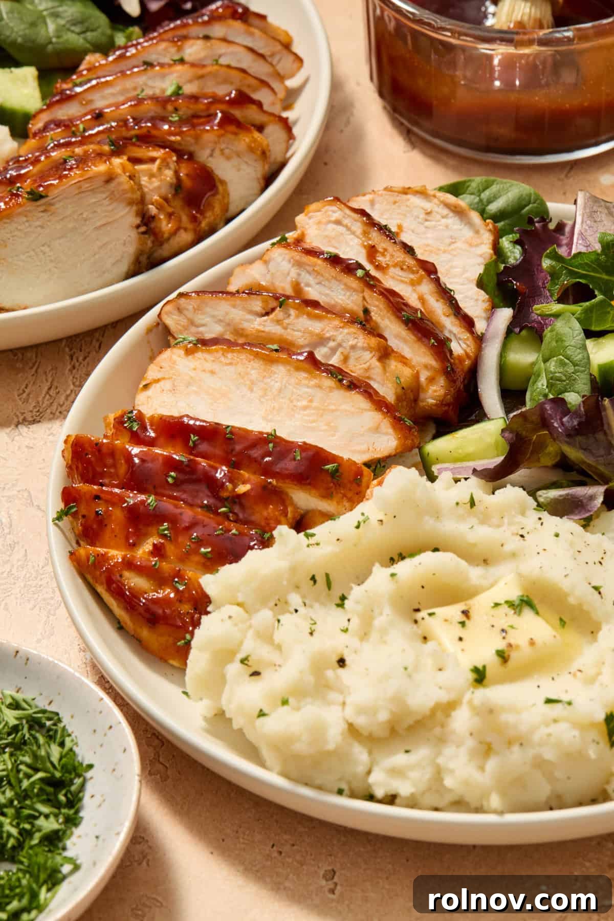 Sliced chicken on plate with mashed potatoes and salad.