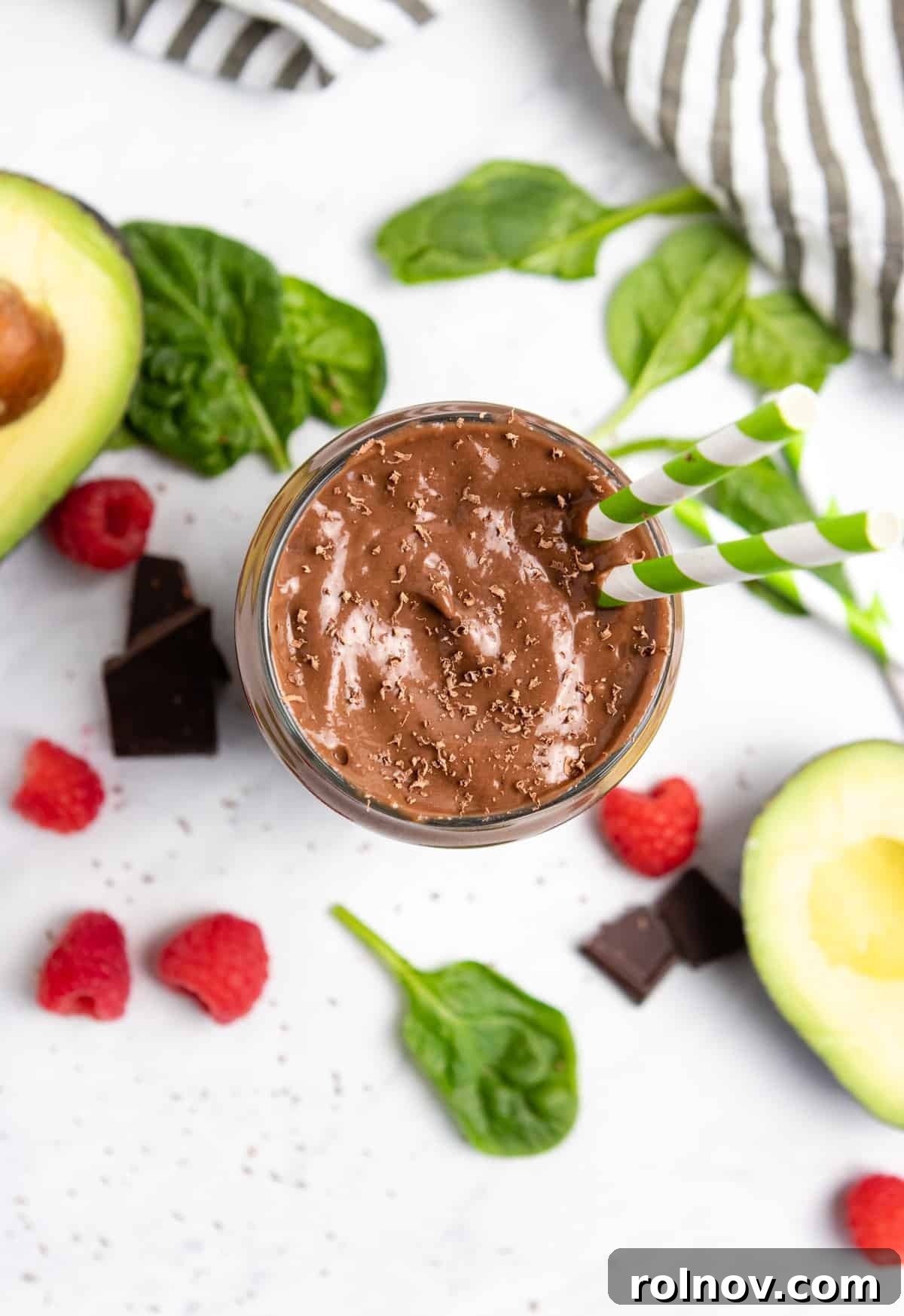 Silky Chocolate Raspberry Avocado Delight 5 Overhead view of chocolate smoothie with spinach, avocado and raspberries next to it.