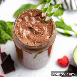 Chocolate raspberry smoothie with avocado and spinach on counter.