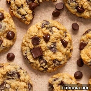 Oatmeal chocolate chip cookies arranged on surface with chocolate chips surrounding.