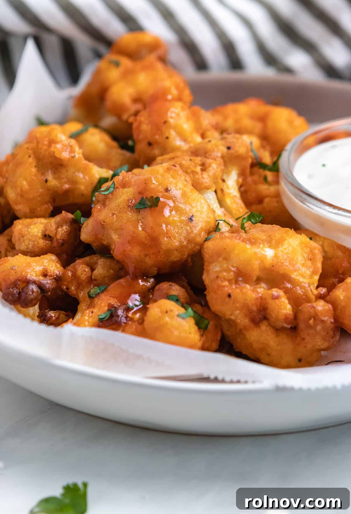 Zesty Air-Fried Buffalo Cauliflower 2 Plate of air fryer buffalo cauliflower with fresh parsley.