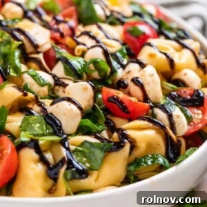 Tortellini Caprese salad in a bowl, generously topped with balsamic glaze.