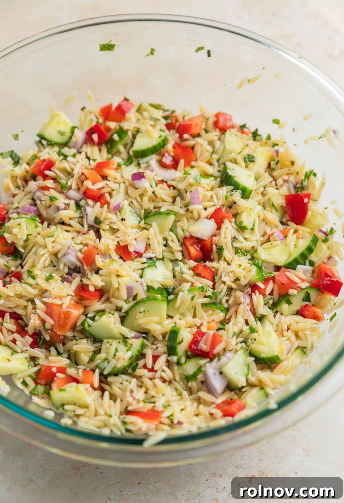 Bright & Effortless Lemon Orzo Salad with Feta 6 Orzo salad ingredients tossed together in glass mixing bowl, before adding feta.